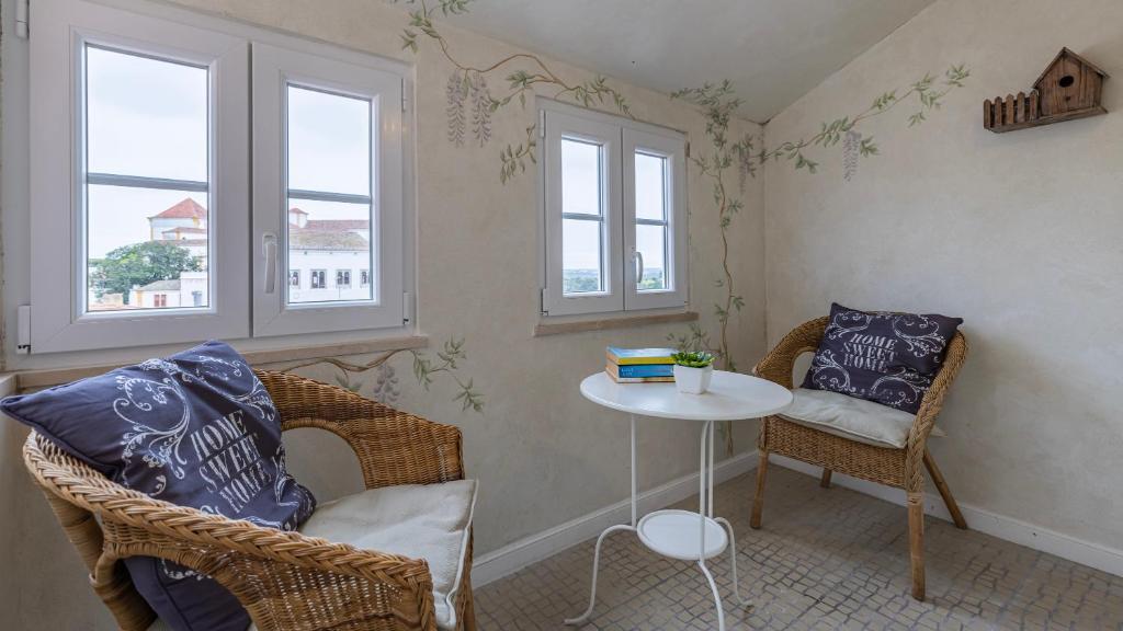 une chambre avec deux chaises, une table et deux fenêtres dans l'établissement Casa do Terreirinho by LovelyStay, à Sintra