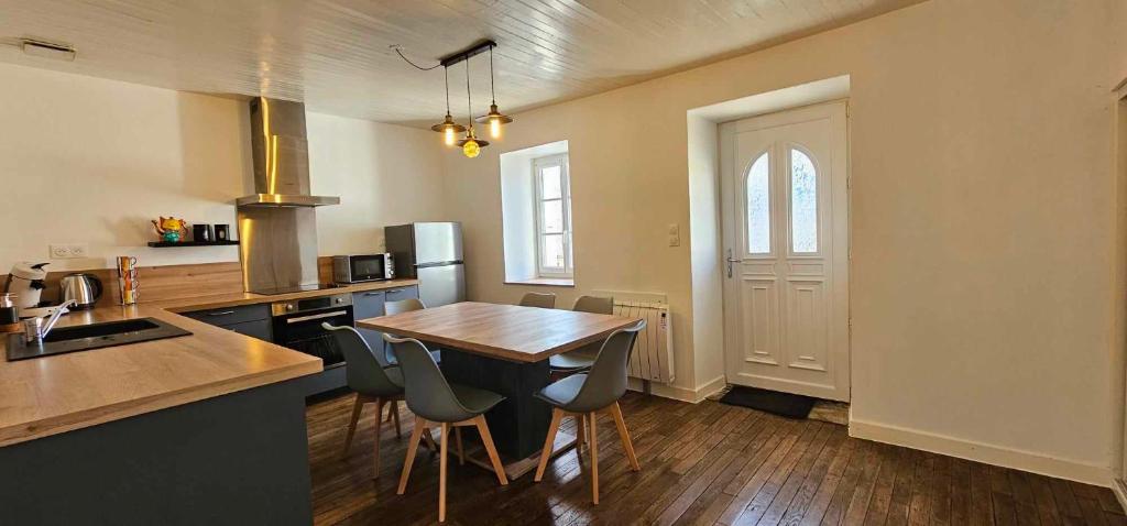 a kitchen with a wooden table and chairs in it at Maison de village in Sadroc