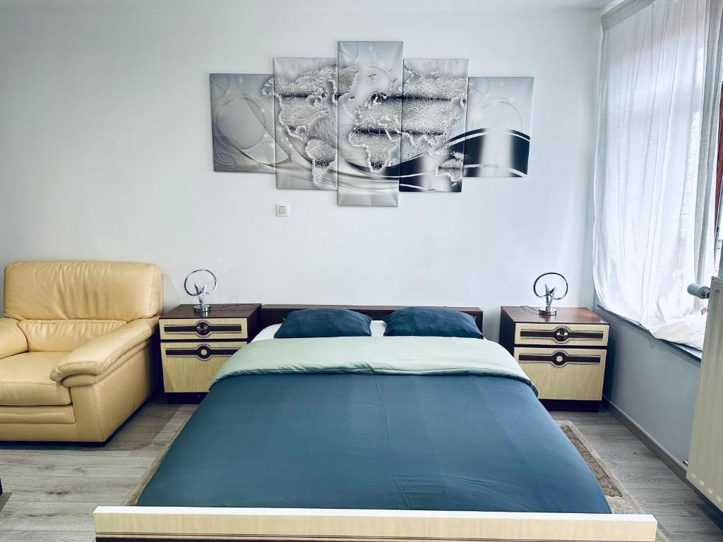 um quarto com uma cama azul e uma cadeira em Chambre et SDD privées dans une maison partagée avec des résidents em Mons