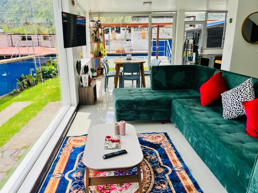 ein Wohnzimmer mit einem grünen Sofa und einem Tisch in der Unterkunft CASA VISTA HERMOSA in Baños