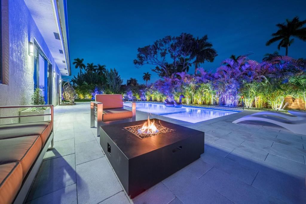 einen Hinterhof mit einer Feuerstelle und einem Pool in der Unterkunft Luxury Villa Amara w/Heated Pool/Sauna/Gym/BBQ in Miami