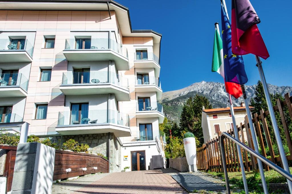 Un grand bâtiment blanc avec des drapeaux devant lui dans l'établissement Hotel Au Soleil, à Saint-Vincent