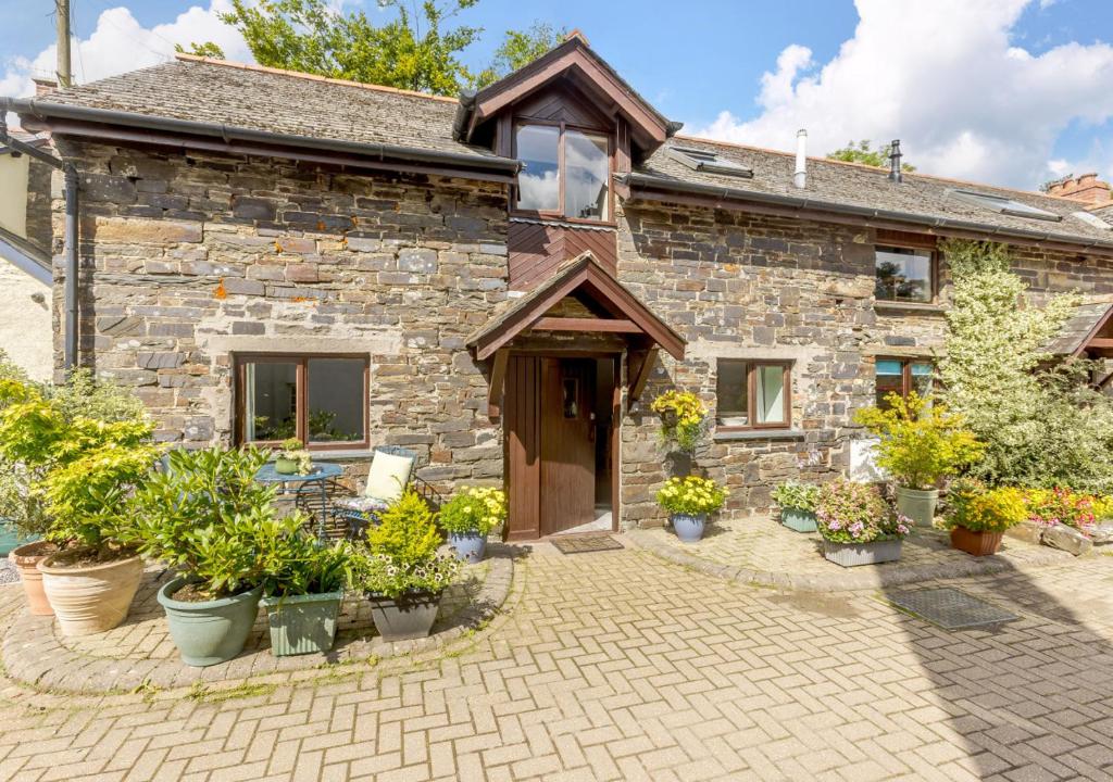 a stone house with potted plants in front of it at Dairy Cottage in Swimbridge