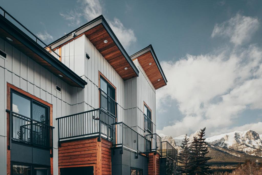 a house with a balcony and mountains in the background at Basecamp Suites Canmore in Canmore