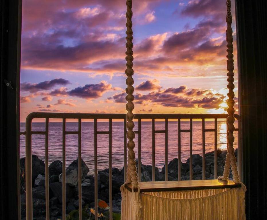 a swing with a view of the ocean at sunset at Claje Sunset! Beachfront condo at Victoria del Mar 1E in Corcega