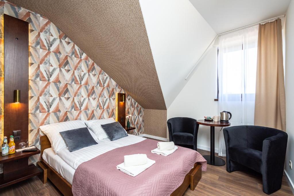 a bedroom with a large bed and two chairs at Hotel i Restauracja Stara Kuźnia in Dobczyce