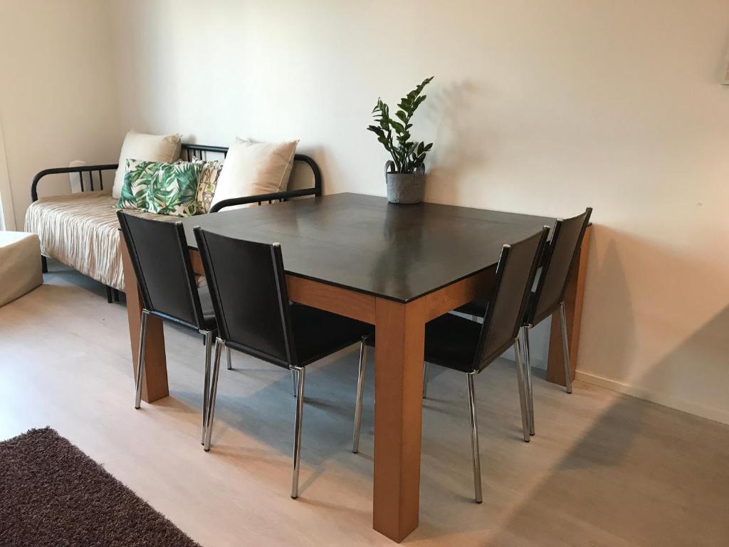 a dining room table with black chairs and a potted plant at Modern Studio, free parking & wifi, Aino Areena 300m in Järvenpää