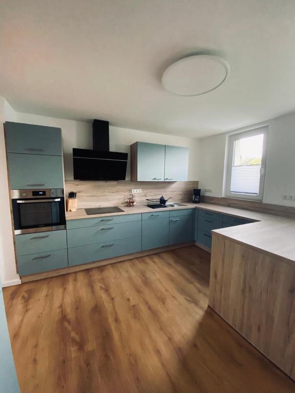 a large kitchen with blue cabinets and wooden floors at Ferienhaus Bleckhausen in Bleckhausen