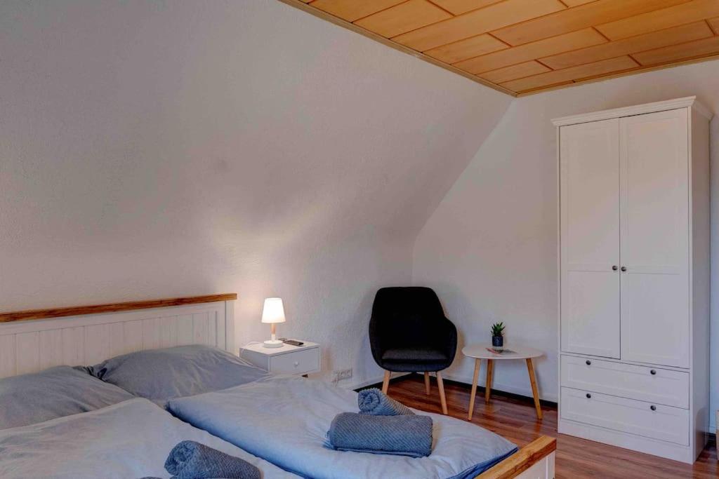 a bedroom with a bed and a black chair at Gemütliche Wohnung nähe Alsfeld - Parkplatz in Alsfeld