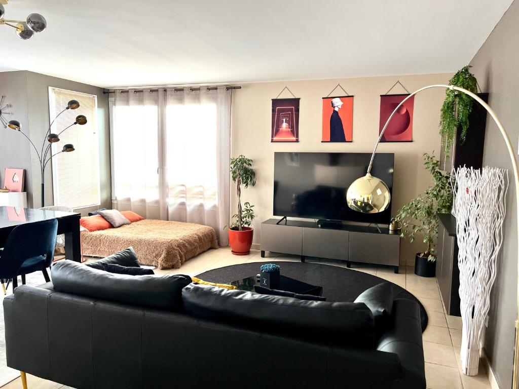 sala de estar con sofá negro y cama en Appartement climatisé T3 chic à Strasbourg avec billard et terrasse, en Estrasburgo