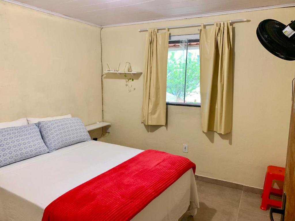 a bedroom with a bed with a red blanket and a window at Morada Massala - Abraão - IG in Abraão