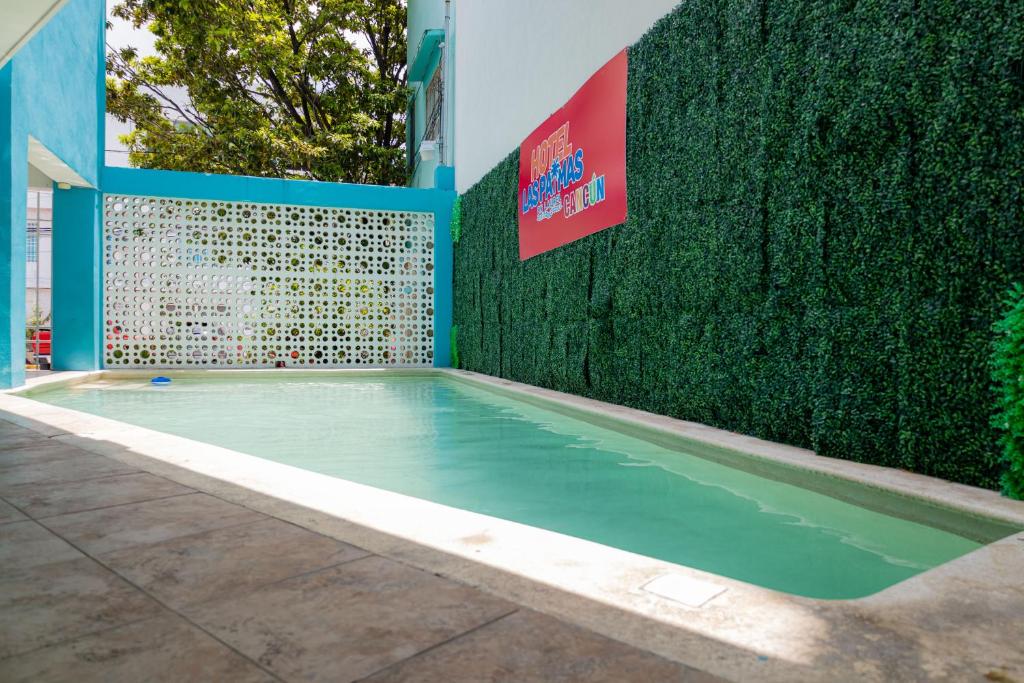 a swimming pool in front of a green hedge at Hotel Las Palmas en Laurel in Cancún