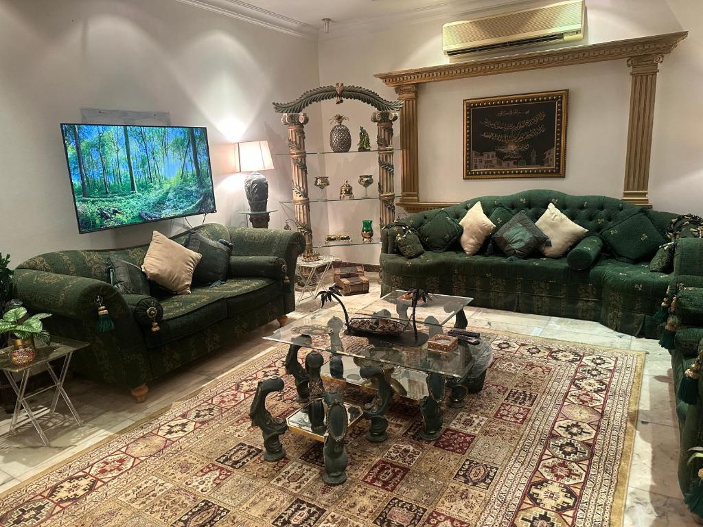 sala de estar con sofás verdes y mesa en دور بغرفتين نوم في المحمدية شمال الرياض en Riad