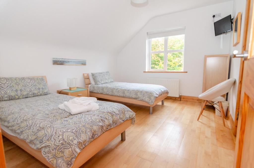 a bedroom with a bed and a chair and a window at Rathmullan Village Home in Rathmullan