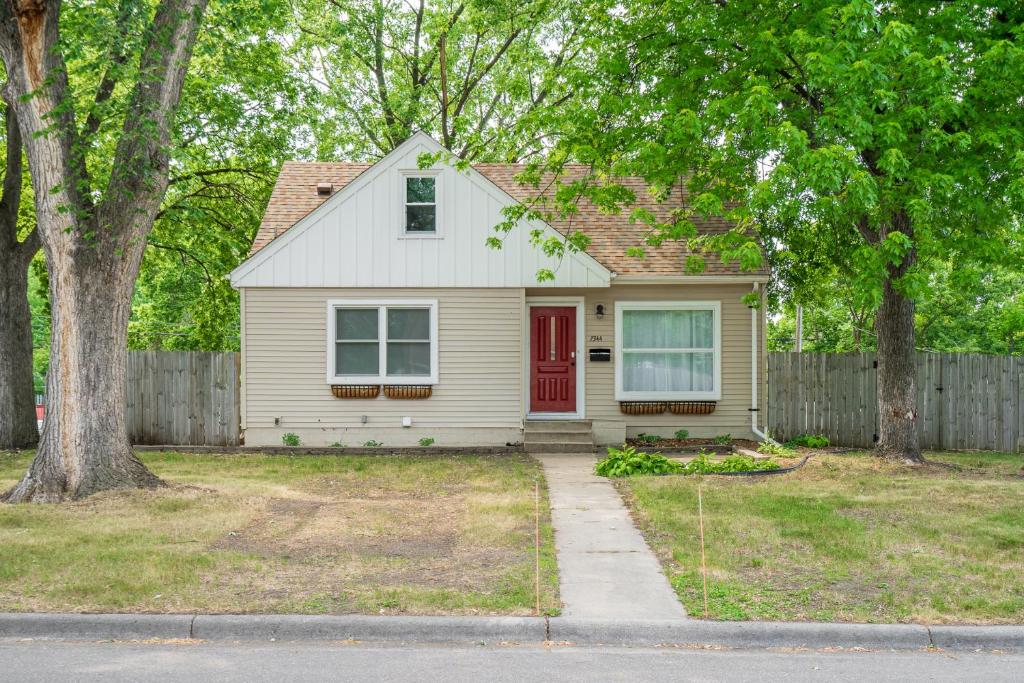 una casa blanca con una puerta roja y una valla en Contempo Cottage, en Minneapolis