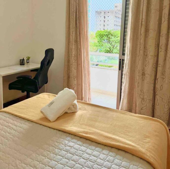 a bedroom with a bed with a chair and a window at Pérola do Aquarius in São José dos Campos