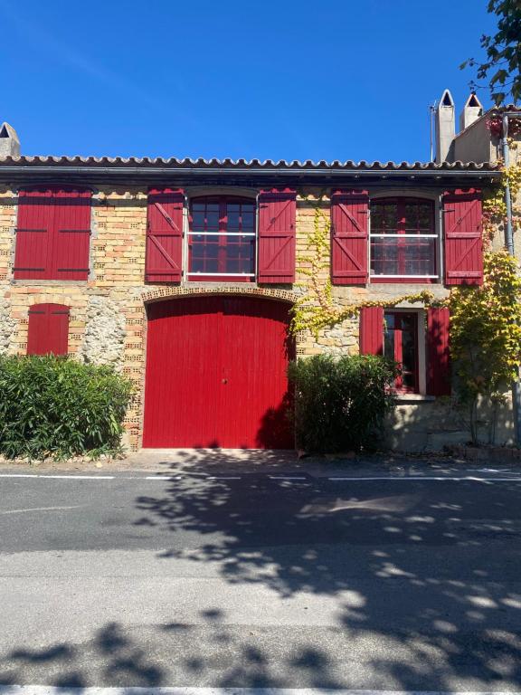 a red brick building with a red garage at Maison de village in Fanjeaux