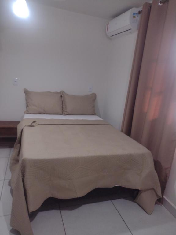 a small bedroom with a bed with a brown blanket at Residencial santiago in Porto Seguro