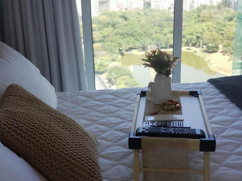 a bed with a table with a keyboard and a window at Nature - Easy Life - Vaca Brava in Goiânia