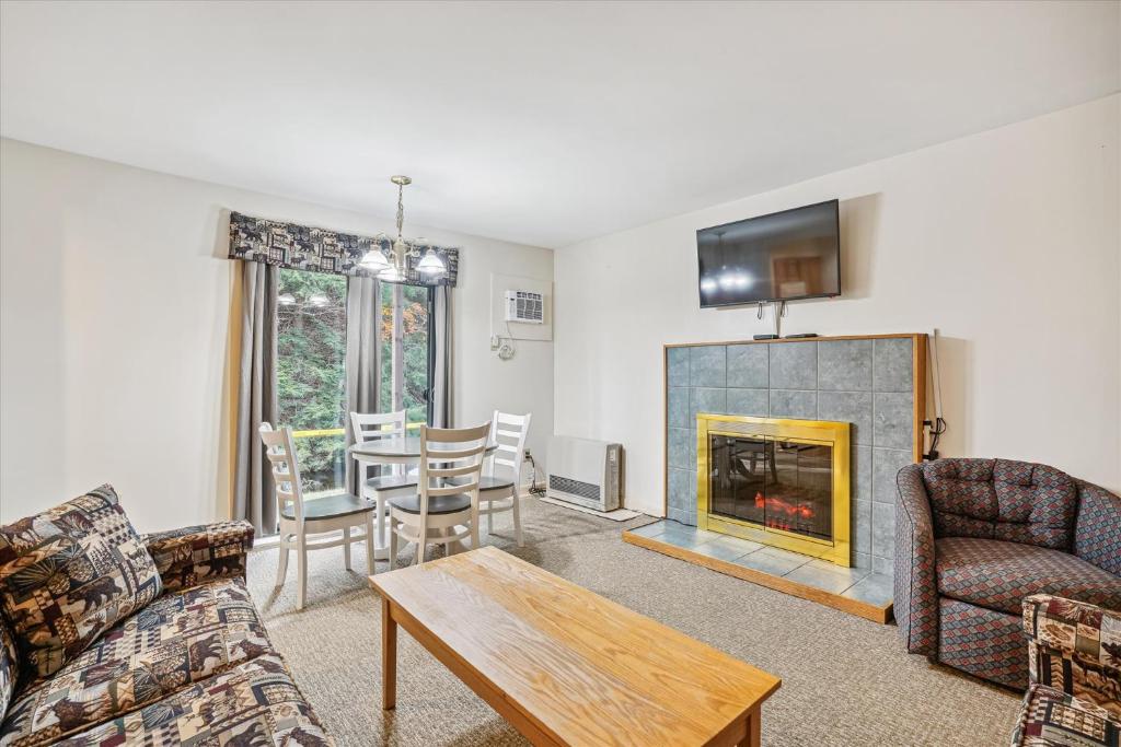 a living room with a fireplace and a table at Cedarbrook Queen Suite 108 in Killington