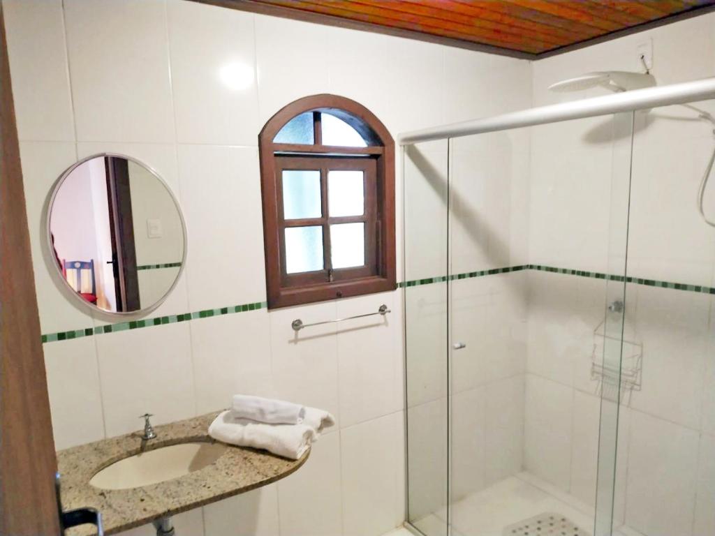a bathroom with a shower and a sink and a mirror at Pousada Kokopelli in Lavras Novas