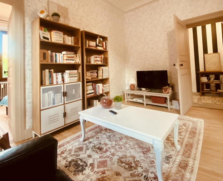 a living room with a white table and a tv at LA MARIEFACTURE - Comme un Livre Ouvert in La Petite-Pierre