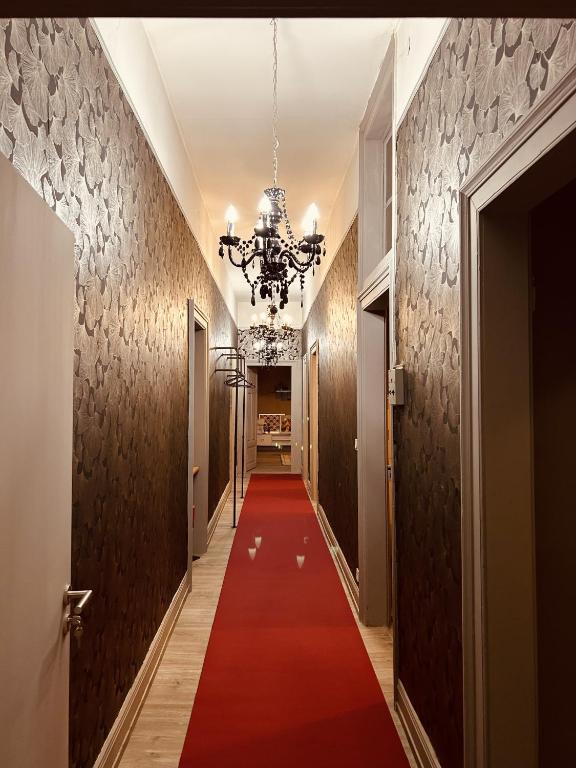 un couloir avec un tapis rouge et un lustre dans l'établissement LA MARIEFACTURE - Comme à l'Opéra, à Neuf-Brisach