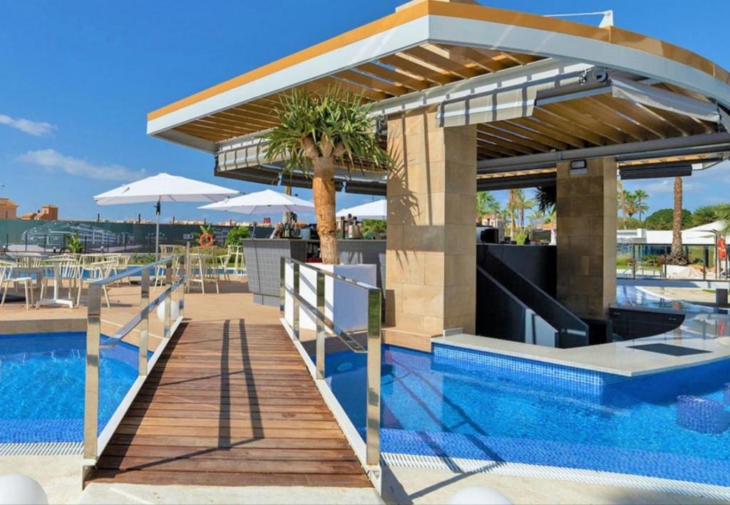 a pool with a wooden deck next to a swimming pool at Lovely first floor apartment, heating pool ! in Playa Flamenca