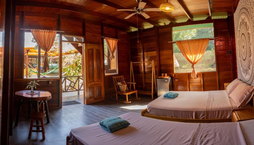 1 Schlafzimmer mit 2 Betten, einem Tisch und Fenstern in der Unterkunft Aroldo Amazon Lodge in Puerto Maldonado