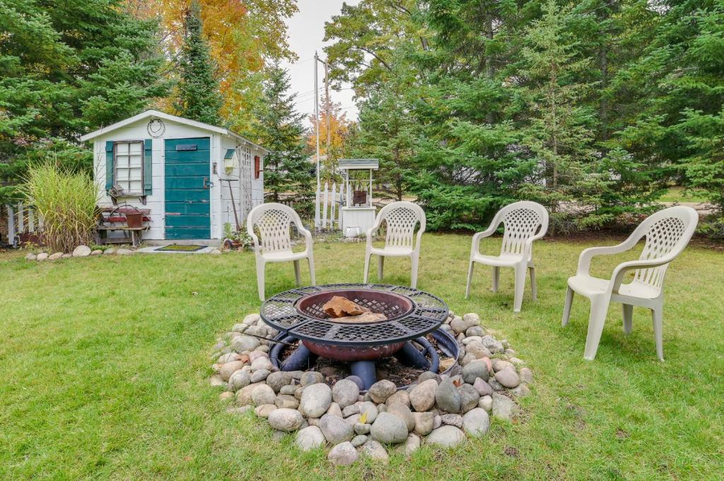 a fire pit in a yard with chairs and a shed at Roscommon Cottage - Walk to Higgins Lake! in Roscommon