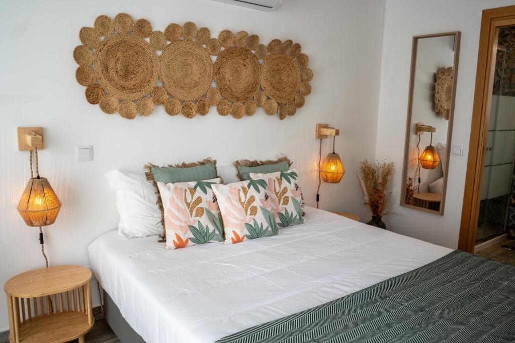 um quarto com uma grande cama branca com almofadas em Tavira Nomad Guesthouse em Tavira