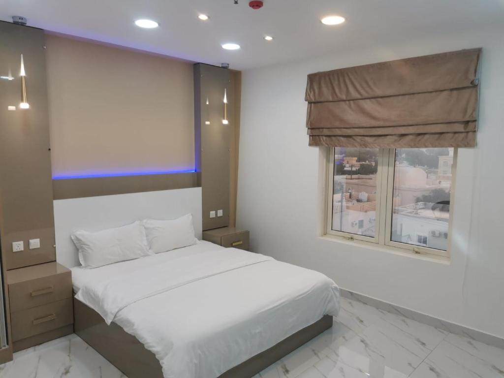 蘇哈爾的住宿－Marina Town，卧室配有白色的床和窗户。