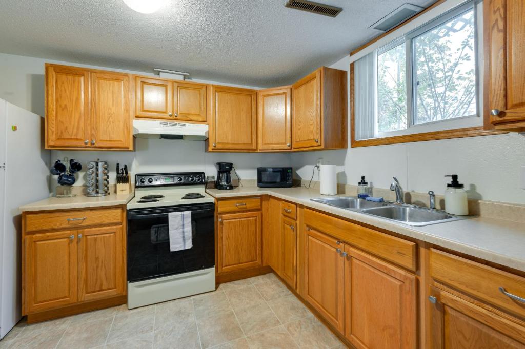 a kitchen with wooden cabinets and a stove and sink at Cedar Rapids Vacation Rental 2 Mi to Downtown! in Cedar Rapids