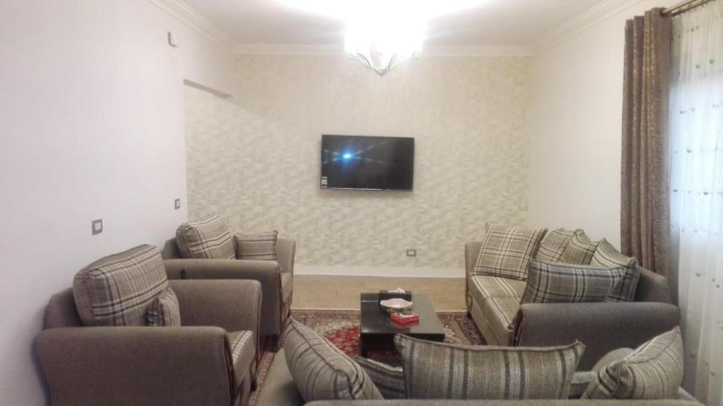 een woonkamer met banken en een tv aan de muur bij Cozy fully well furnished apartment for rent in Mesaha Square - Dooki in Caïro