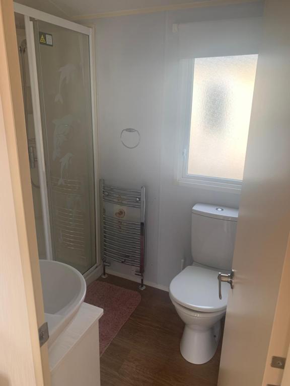 baño con aseo y lavabo y ventana en Issacs Retreat Skipsea Sands, en Ulrome
