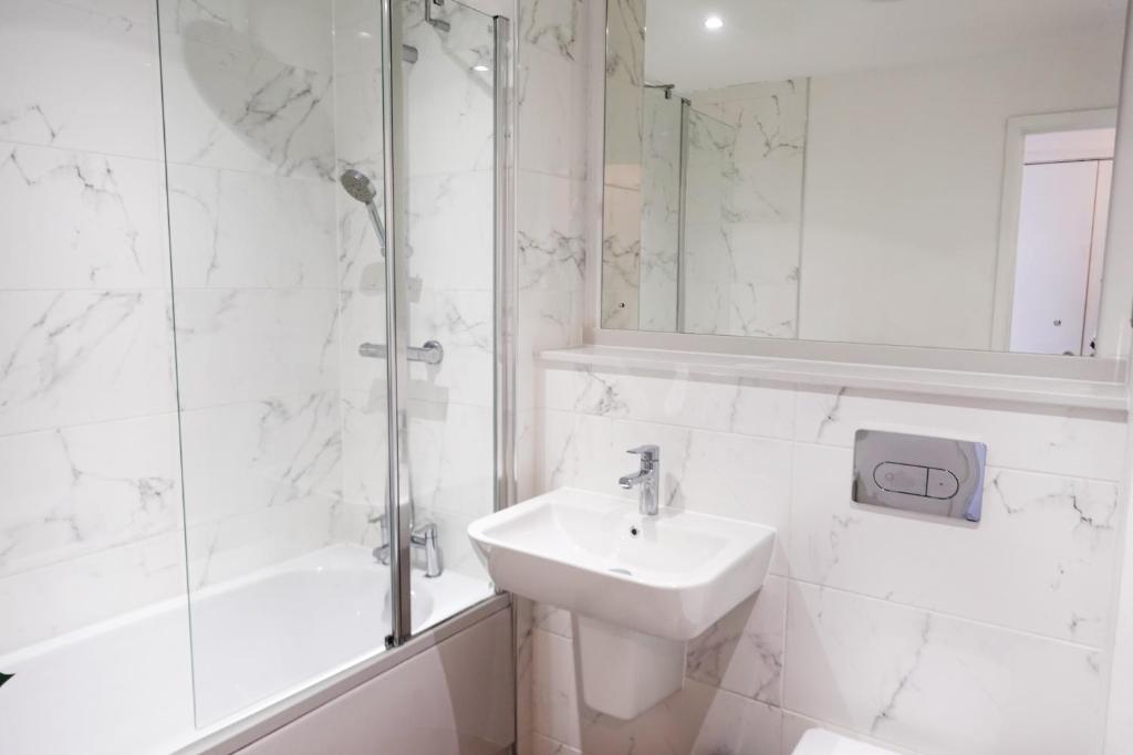 a white bathroom with a sink and a shower at Luxury 2 Bedroom Apartment, Broad street Birmingham in Birmingham