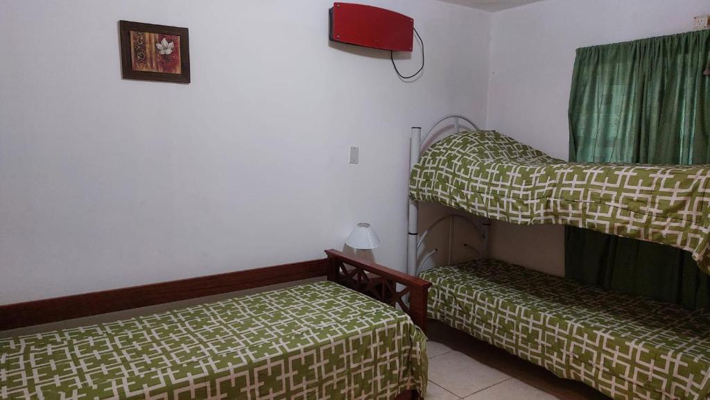 een kamer met 2 bedden en een groen gordijn bij Cabañas Rincón Potrero in Potrero de los Funes