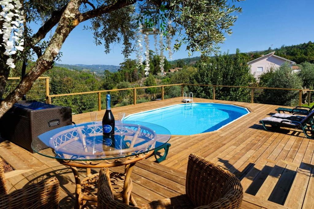 a table with a bottle of wine on a deck with a pool at Quinta Refúgios do Rio Dão in Mangualde