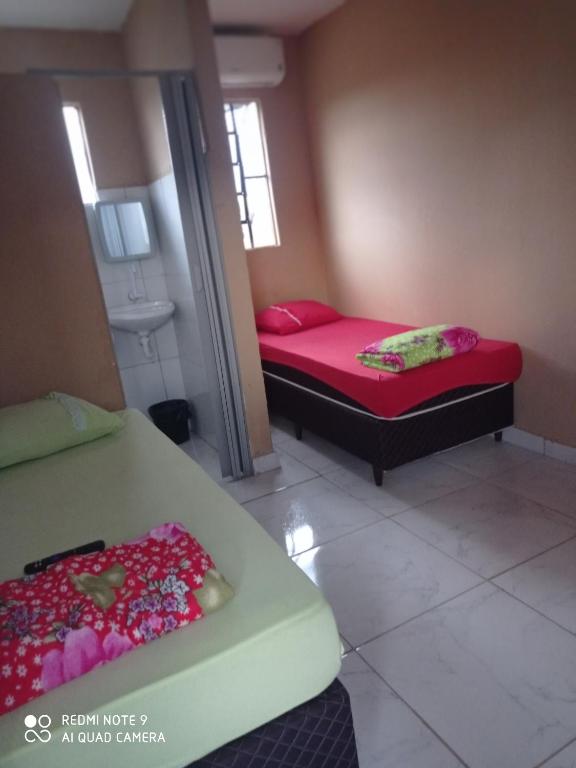 2 camas en una habitación pequeña con sábanas rojas en Hotel Veneza, en Ribas do Rio Pardo