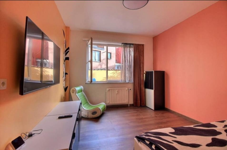 a bedroom with orange walls and a bed and a window at Chambre chez Anita in Brussels