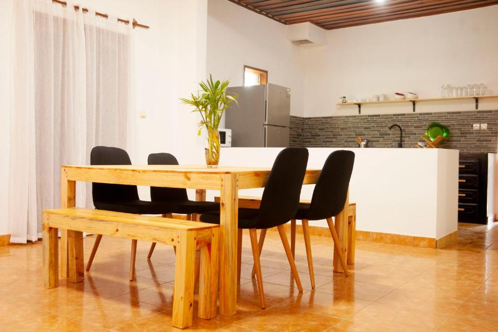 a wooden table with black chairs and a kitchen at VILLA TIARÉ DIEGO in Antsakomboena