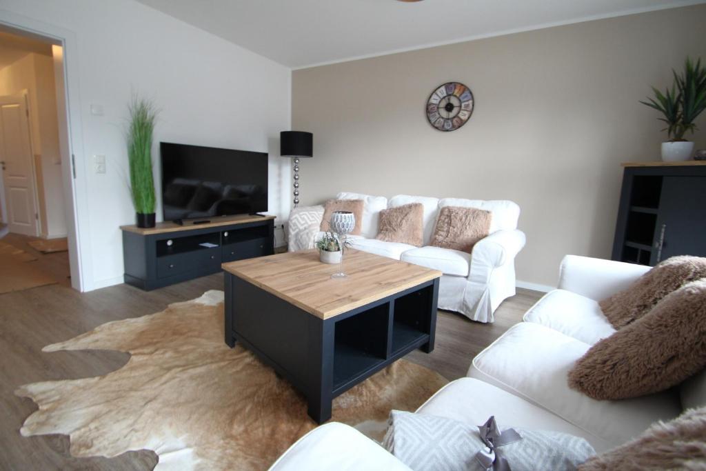 a living room with white couches and a coffee table at Sunseeker House 2 in Bad Schwartau