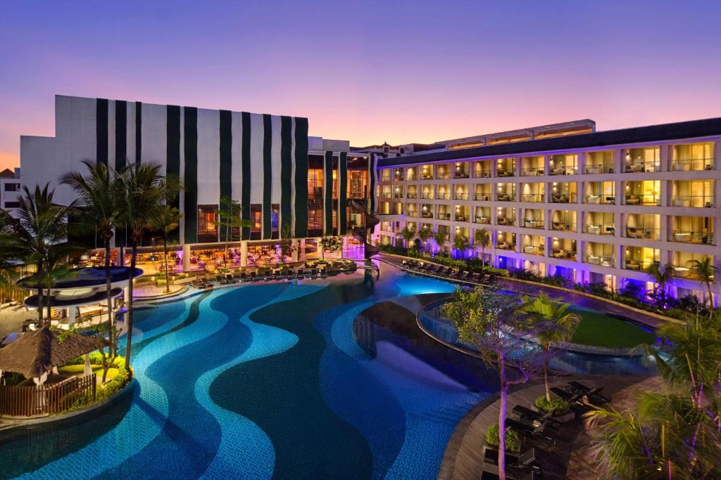 un hotel con piscina frente a un edificio en The Stones Hotel - Legian Bali, Autograph Collection, en Kuta