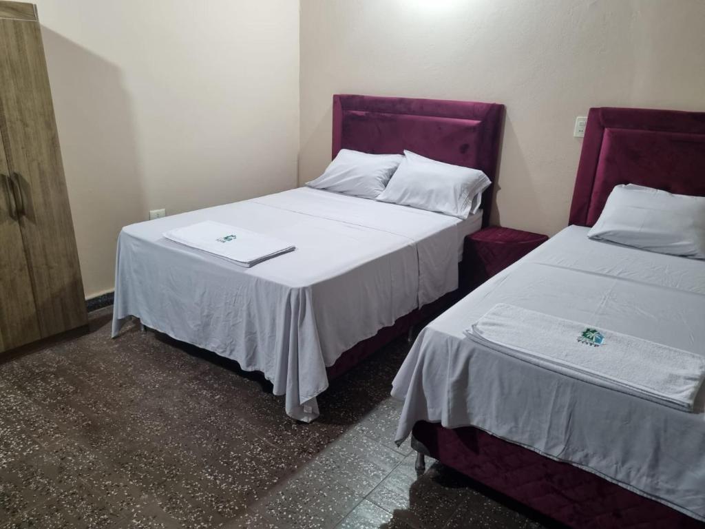 2 Betten in einem Zimmer mit Weiß- und Lilatönen in der Unterkunft Hostal Lo de Tote in Villa Concepción