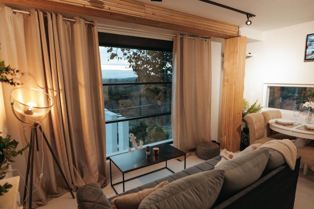 een woonkamer met een bank en een groot raam bij Calm House Villa in Prijedor