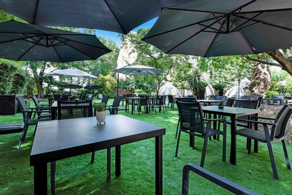 a group of tables and chairs with umbrellas at Doubletree By Hilton London Kensington in London