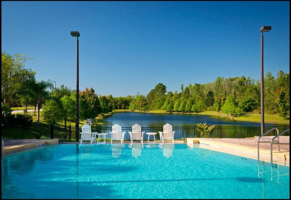 een groot zwembad met stoelen en een meer bij 9055 Resort Gem Condo-3 bed/2ba in Kissimmee