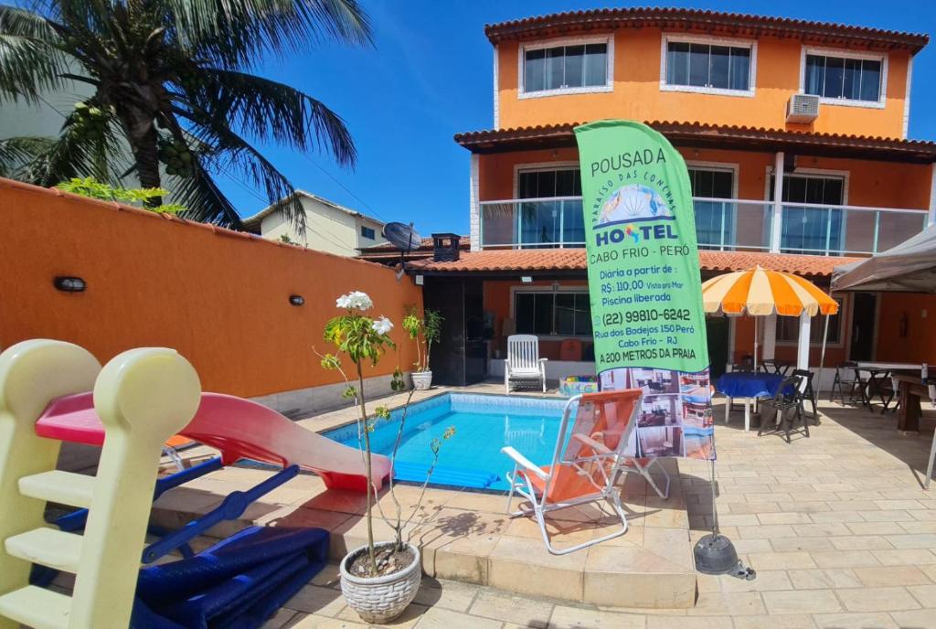 a swimming pool with a sign next to a building at Pousada Paraíso das Conchas na praia do Peró Cabo Frio RJ in Cabo Frio