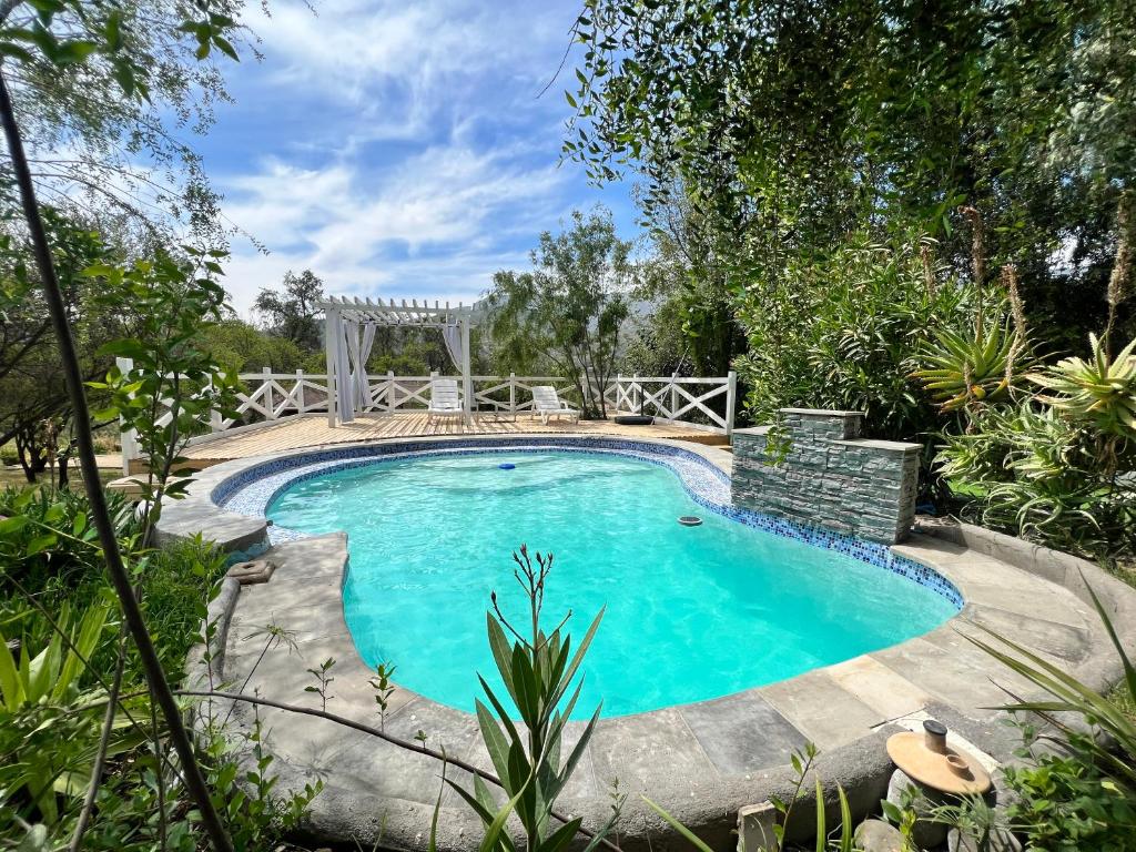 una piscina en un jardín con pérgola en Hermosa Casa con piscina “El Paraíso” en Viña Guzmán