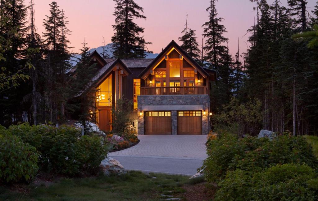 a home with a lit up garage at dusk at Kadenwood 2972 - Mountain Chalet, w/ Hot Tub, Pool Table, Fireplace - Whistler Platinum in Whistler